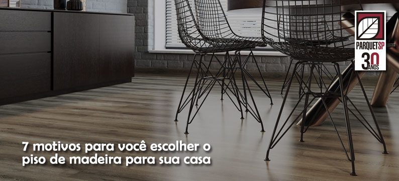 Ao fundo da imagem, há uma sala com uma mesa, duas cadeiras e piso de madeira.