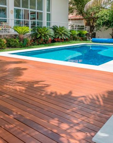 A imagem mostra a area externa de uma casa com um deck de madeira ao redor da piscina.
