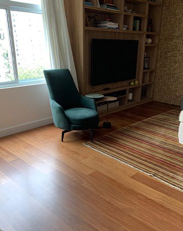 A imagem mostra um ambiente com piso de madeira e uma poltrona.