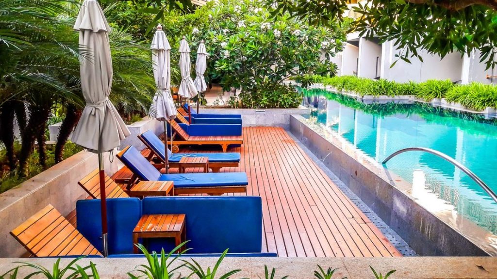 Ao fundo da imagem, há uma piscina com deck de madeira.