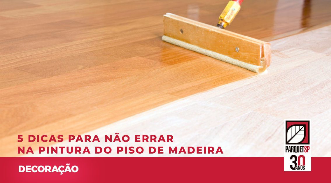 Ao fundo da imagem, há um rodo pintando o piso de madeira.