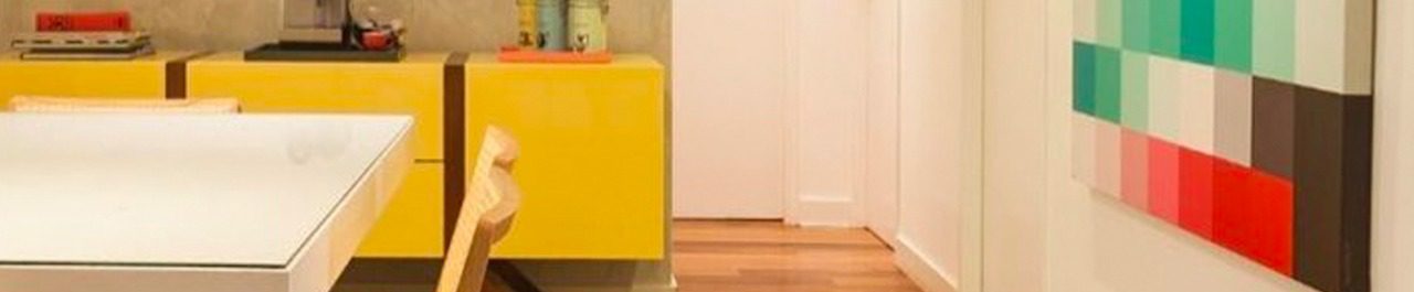 Ao fundo da imagem, há uma sala de jantar com piso de madeira e um móvel amarelo.