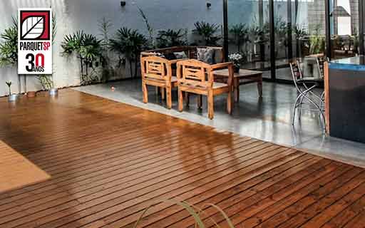 Ao fundo da imagem, há um deck de madeira em área interna.