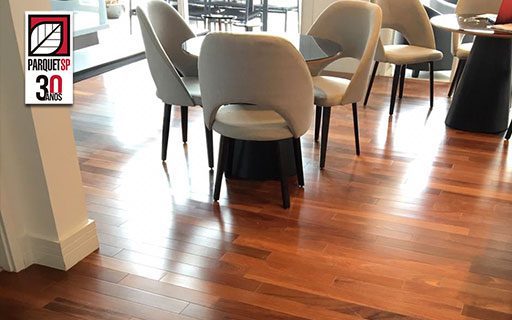 Ao fundo da imagem, há uma sala de jantar com o piso de madeira cumaru.