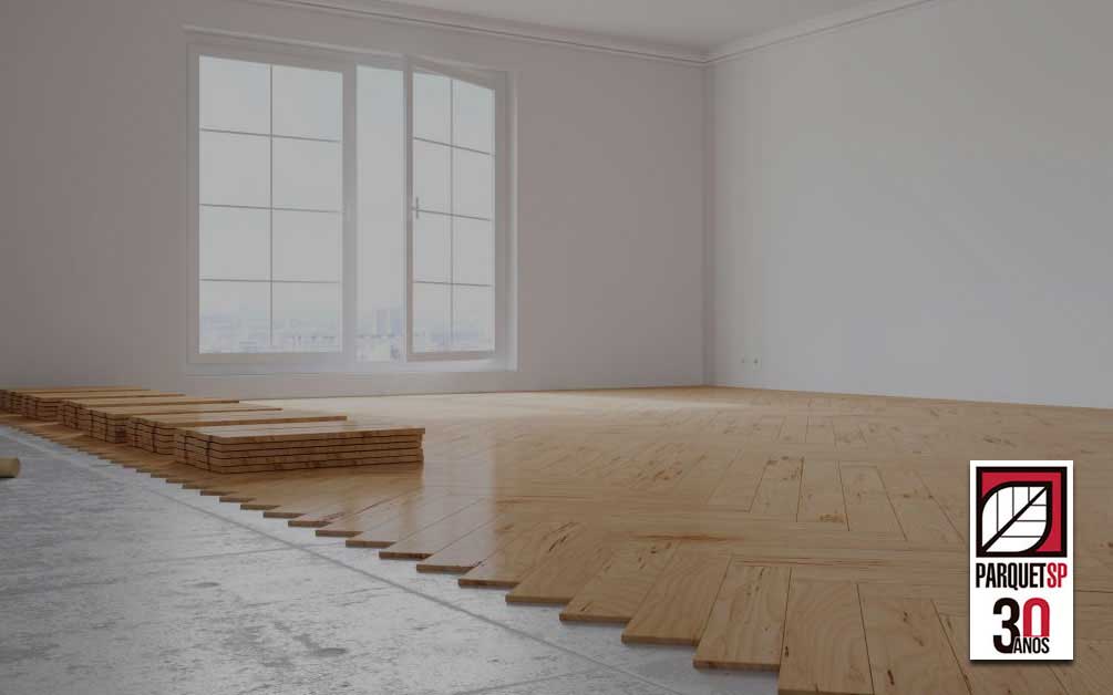 Ao fundo da imagem, há uma sala com o piso de madeira sendo aplicado.