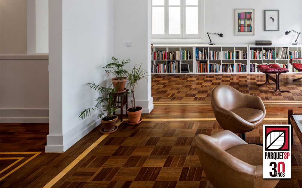 Ao fundo da imagem, há uma sala com piso de madeira parquet.