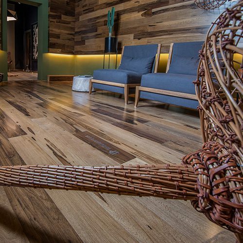 Sala moderna com piso de madeira, poltronas e decoração em tons naturais, destacando acabamento e design do ambiente.