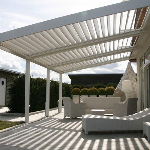 Área externa com pergolado de madeira branco, móveis de jardim e iluminação natural criando um ambiente aconchegante e moderno.