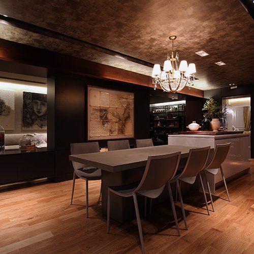 Sala de jantar moderna com mesa longa, cadeiras elegantes, piso de madeira e iluminação aconchegante em ambiente sofisticado.