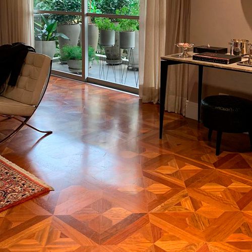 Imagem ilustra uma sala de estar, com um piso de Carvalho Europeu, em que a iluminação da sala, reflete sobre o piso.