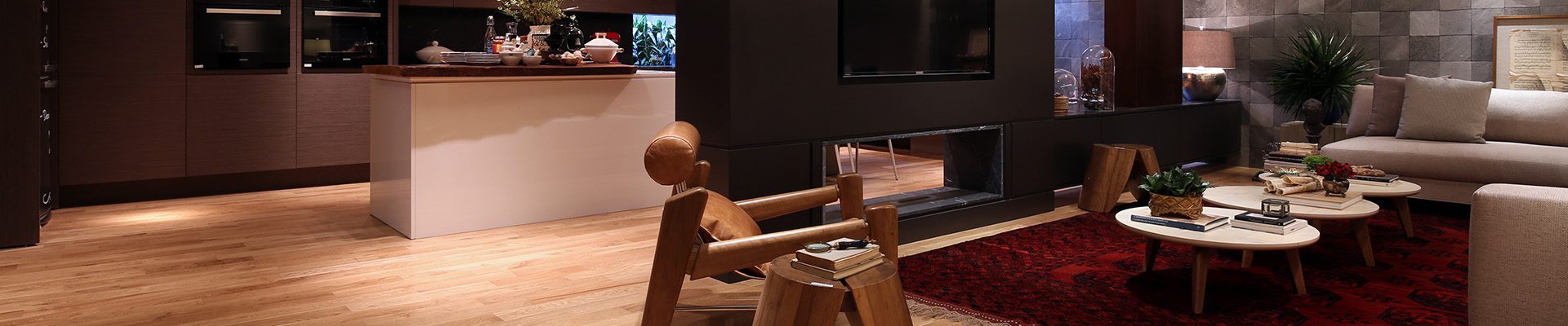 Sala moderna com piso de madeira clara, decoração aconchegante, móveis de design único, iluminação embutida e tapete vermelho, criando um ambiente sofisticado e acolhedor.