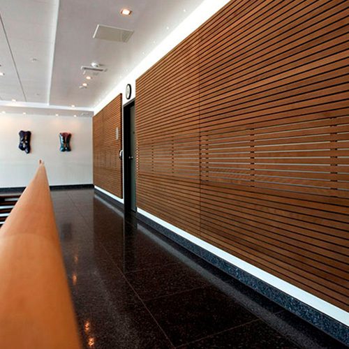 Parede revestida com brise de madeira em um ambiente moderno, proporcionando sofisticação, controle de luminosidade e conforto térmico.