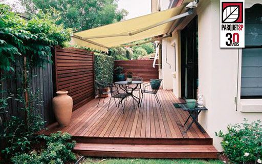 Ao fundo da imagem, há um deck de madeira no terraço de uma casa.