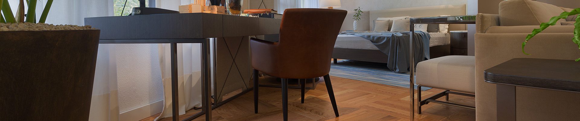 Ambiente interno com piso de taco de madeira, mesa de trabalho elegante e decoração moderna, criando um ambiente acolhedor e sofisticado.