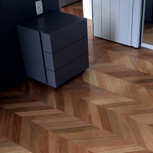a imagem ilustra um piso de madeira tauari e uma mesa de cabeceira preta