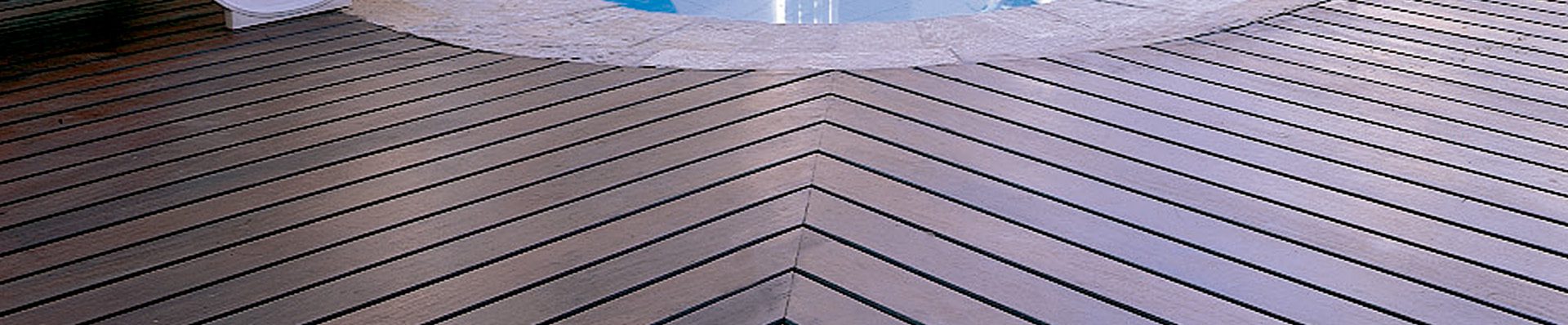 Imagem de um deck de madeira ao redor de uma piscina, com design em padrão geométrico. Ideal para destacar elegância e qualidade de materiais em áreas externas e piscinas.