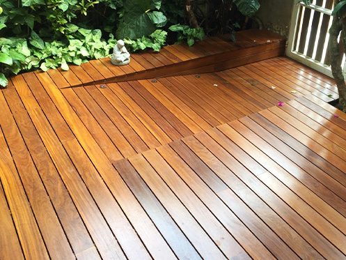 Imagem ilustra um Deck de madeira, aplicado em um jardim.