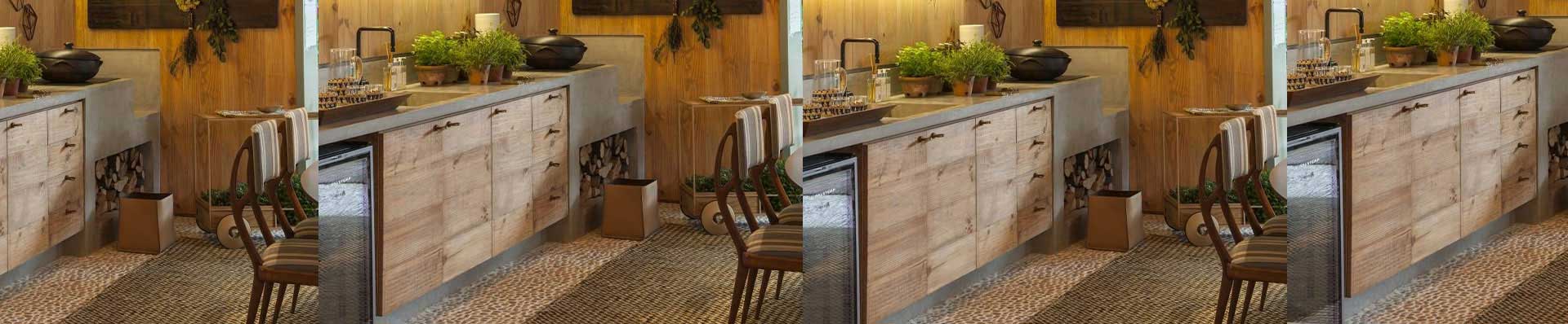 A imagem mostra uma cozinha rústica com painel e gavetas de madeira.