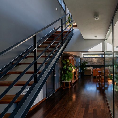 Escada de madeira com estrutura metálica em ambiente residencial moderno, integrando design, iluminação natural e conforto.