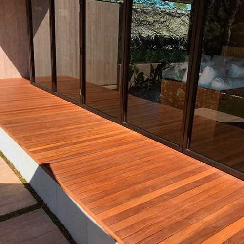 Deck de madeira instalado junto a portas de vidro, com acabamento natural e área externa integrada, em projeto residencial moderno.