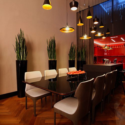 Ambiente interno sofisticado com piso de taco de madeira, mesa de jantar moderna, cadeiras estofadas e iluminação pendente aconchegante.