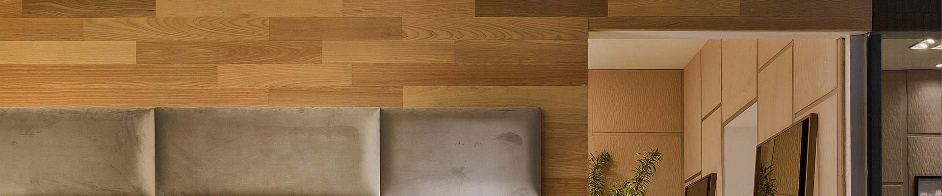 Quarto sofisticado com revestimento de madeira, cabeceira estofada em tons neutros, mesa lateral com abajur e mesa de jantar elegante ao lado.