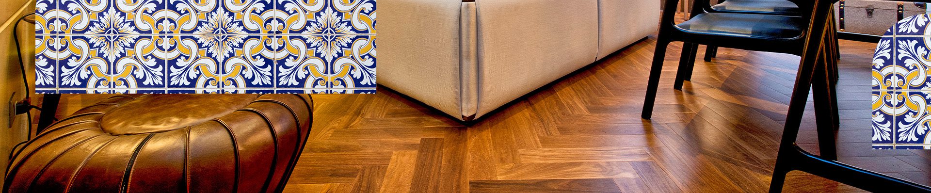 Sala de estar com decoração aconchegante, apresentando piso de madeira em padrão espinha de peixe e parede com azulejos portugueses azuis e amarelos em destaque.
