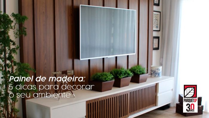 A imagem mostra uma sala com painel de madeira de tv, uma tv pendurada, e um rack.