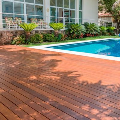 A imagem mostra a area externa de uma casa com um deck de madeira ao redor da piscina.