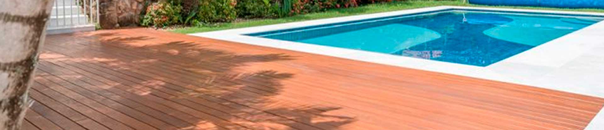 A imagem mostra a area externa de uma casa com um deck de madeira ao redor da piscina.