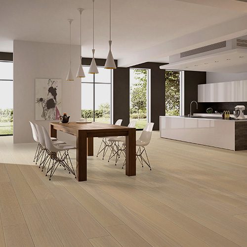 Sala de jantar integrada à cozinha com piso de madeira clara, mesa com cadeiras e iluminação pendente em ambiente moderno.