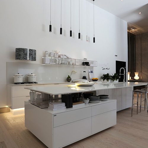 Cozinha moderna com ilha central, armários brancos e iluminação pendente, em ambiente sofisticado e bem organizado.