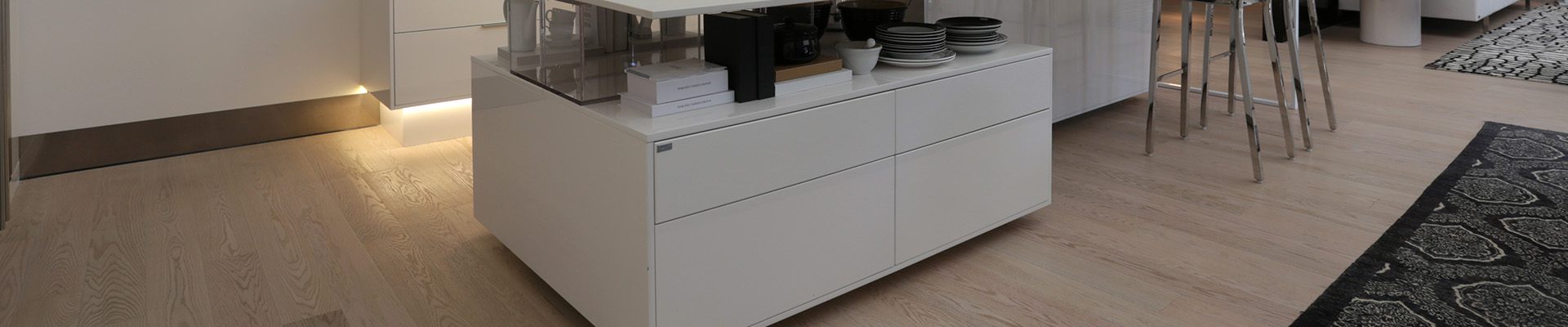 Cozinha moderna com ilha central, armários brancos e iluminação pendente, em ambiente sofisticado e bem organizado.