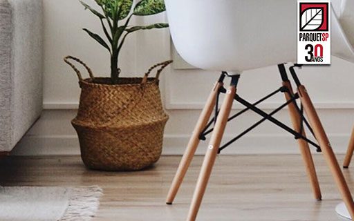 Ao fundo da imagem, há uma sala de estar integrada com um piso de madeira clara.