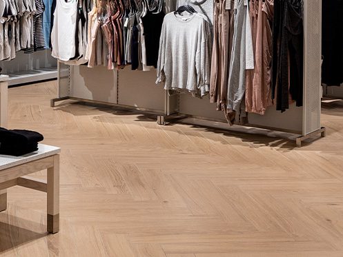 Imagem ilustra uma loja de roupas com piso de madeira
