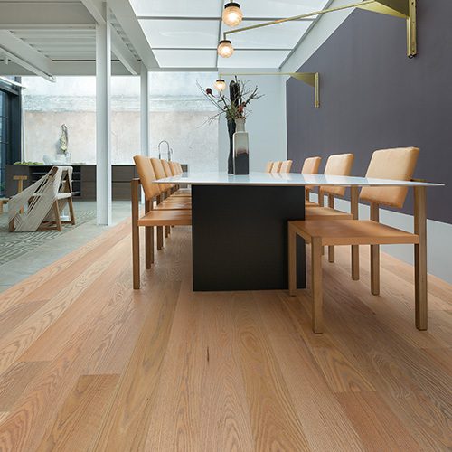 Sala de jantar moderna com piso de madeira clara, mesa retangular preta e cadeiras de madeira, destacando elegância e design minimalista.