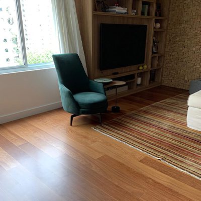 A imagem mostra um ambiente com piso de madeira e uma poltrona.