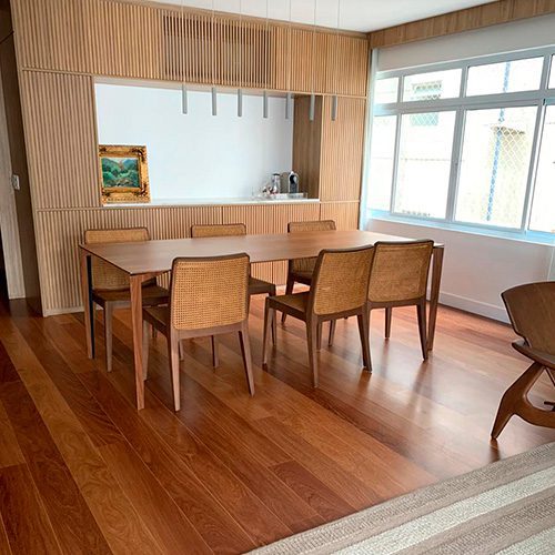 Sala de jantar com piso de madeira e móveis em tons naturais, destacando a elegância e o aconchego proporcionados pelos revestimentos de madeira.