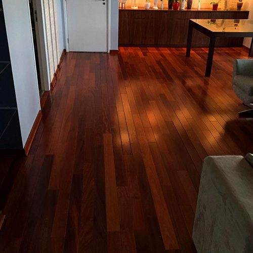Ambiente interno com piso de madeira escura, iluminação aconchegante e acabamento refinado em espaço residencial.