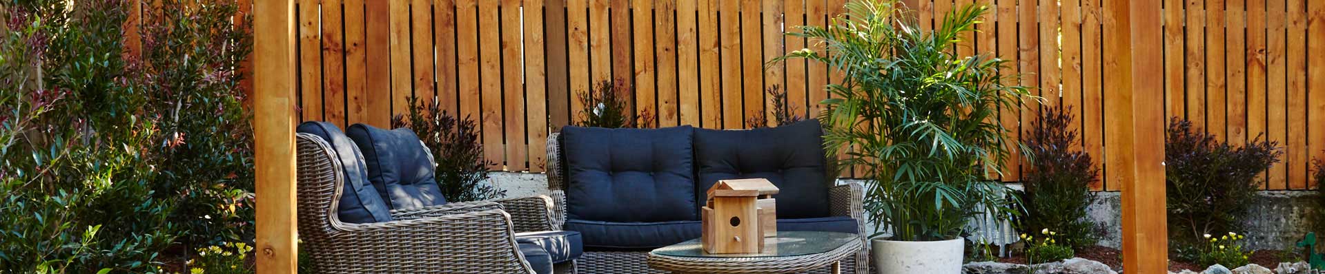 Jardim com sofás, mesa de certo, parede de deck de madeira e pergolado de madeira - ParquetSP