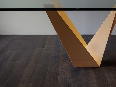 Imagem ilustra um pé de mesa em forma de V, com uma madeira escura.