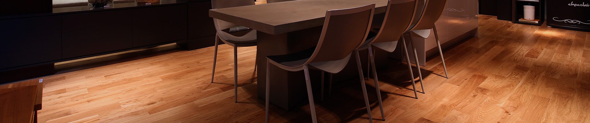 Ambiente interno elegante com piso de madeira teca, mesa de jantar moderna e iluminação quente com lustre central.