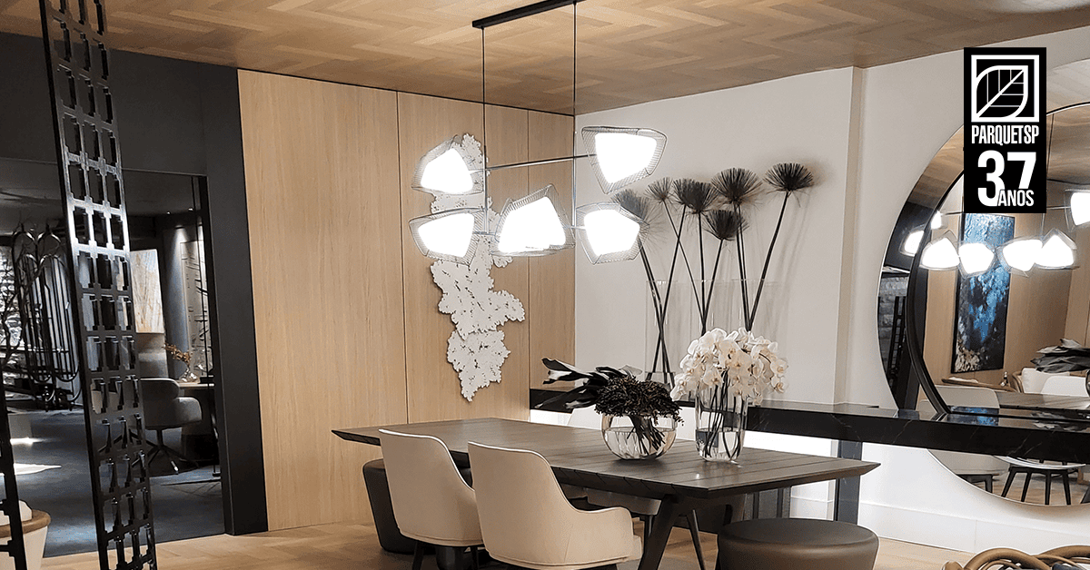 Sala de jantar elegante com mesa de madeira, cadeiras estofadas e forro de madeira no teto, destacando sofisticação e conforto térmico e acústico.