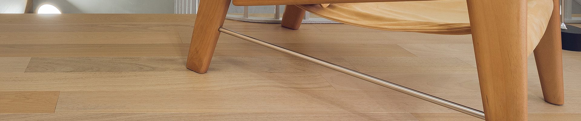 Ambiente moderno com piso de madeira clara, poltrona de design elegante e escada com corrimão metálico. Decoração minimalista e iluminada.