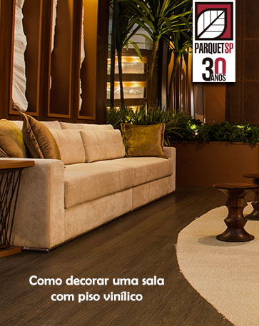 Ao fundo da imagem, tem um sofá claro, piso vinílico e mesa de madeira com um tapete de cor clara.