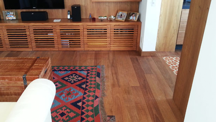 A imagem mostra um ambiente com piso de madeira e alguns móveis com tons combinando com o piso.