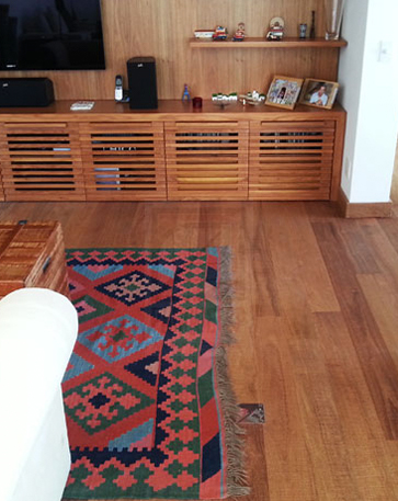 A imagem mostra um ambiente com piso de madeira e alguns móveis com tons combinando com o piso.