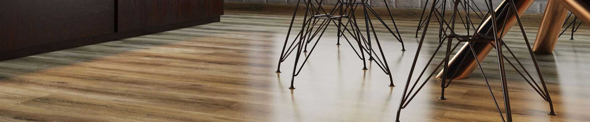 Ao fundo da imagem, há uma sala com uma mesa, duas cadeiras e piso de madeira.